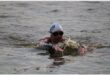 A swimmer in a dam taking part in a triathlon with a cap on.