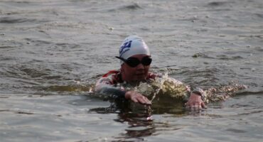 A swimmer in a dam taking part in a triathlon with a cap on.