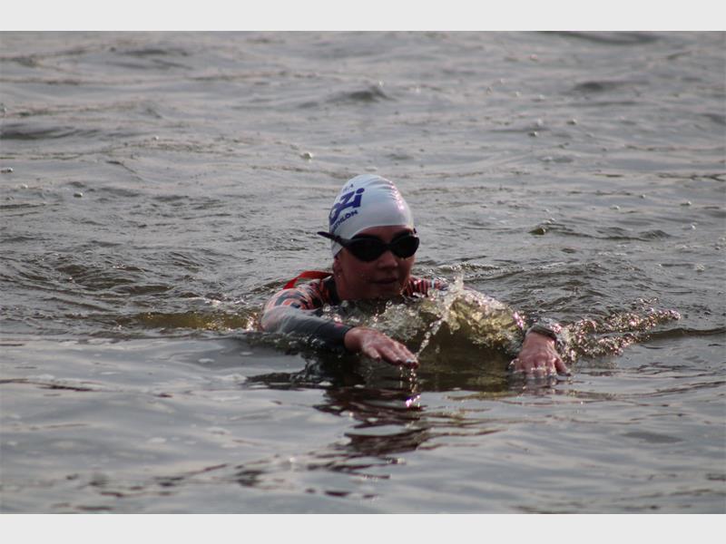 A swimmer in a dam taking part in a triathlon with a cap on.