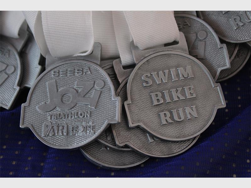 A close-up of silver medals on a table with the words SEESA and Swim, Bike, Run.