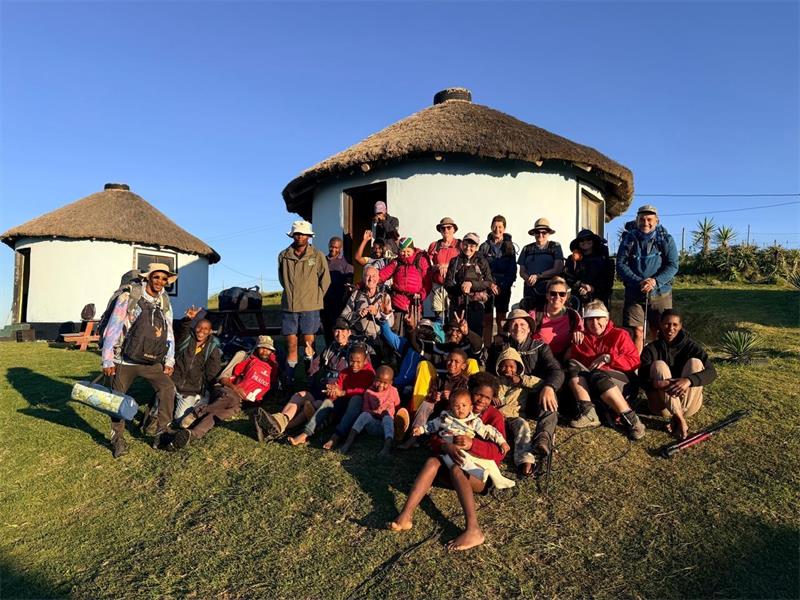 A group of hikers standing in front of a hut house