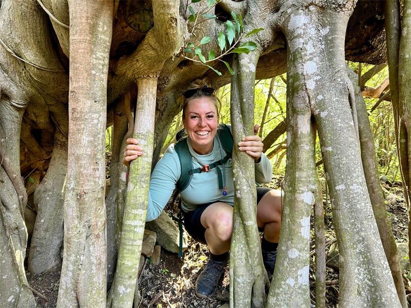Lady bending on the ground while holding trees
