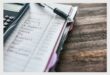 An image of a book with writing on a page and pen lying on top of the page.