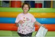 Lady in a pink top and black pants, holding wrapped boxes