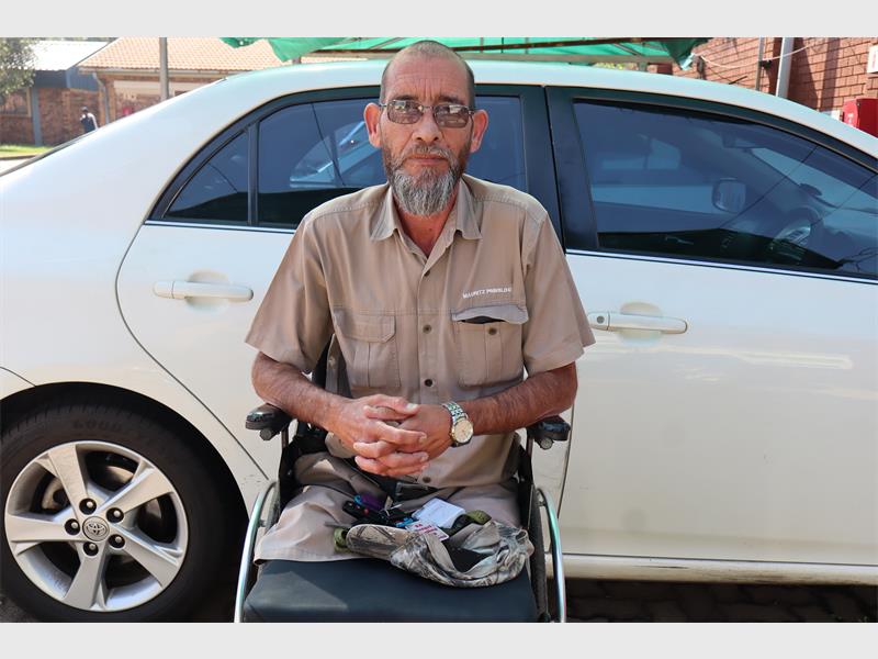 White man with grey bread sitting on a wheelchair.