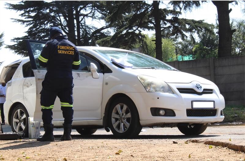 A uniformed officer standing at a white Toyota with its driver's door open