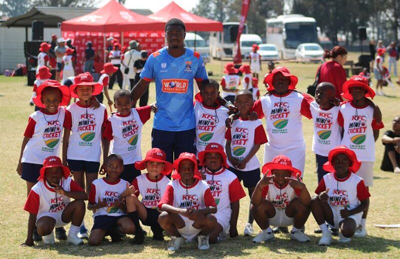 Mini cricket team posing with their coach