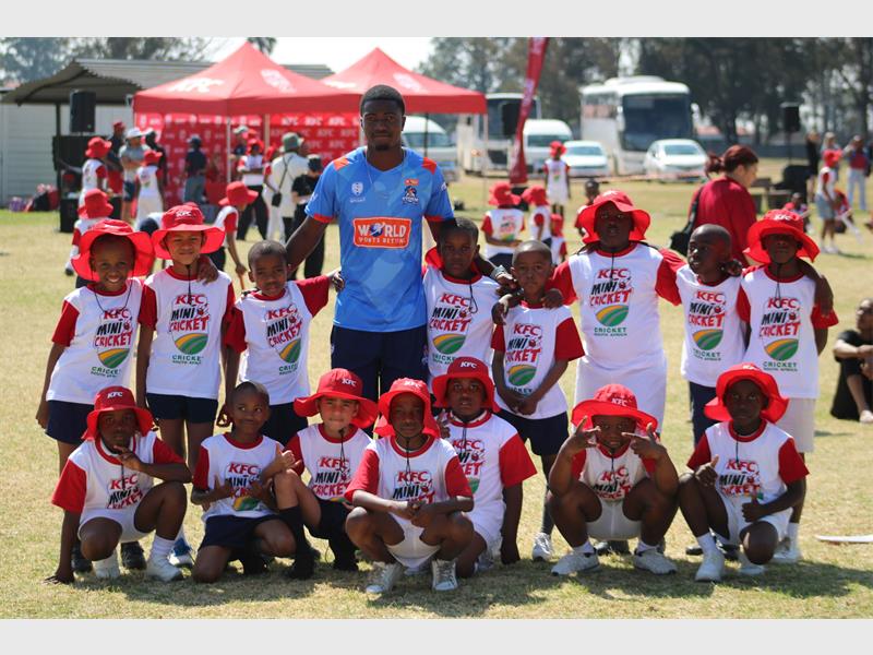 Mini cricket team posing with their coach