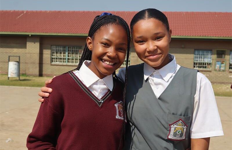 One girl in red uniform standing next to a girl in grey uniform