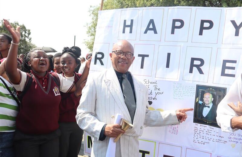 A coloured man in a white suite pointing at the poster.