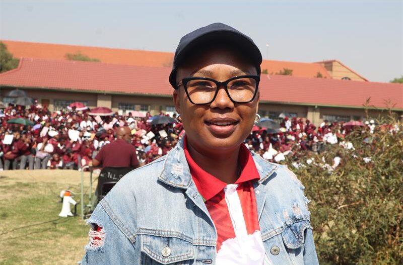 A lady wearing a black cap, white and red top, and a jean jacket