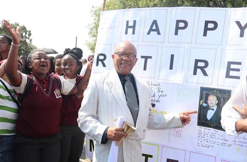 Man in a white suit pointing at a poster.