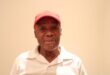 A man wearing a white golf tshirt and a red cap