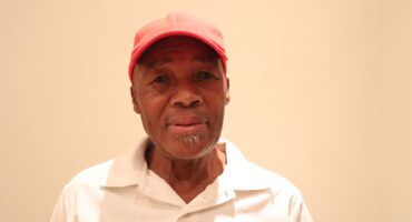 A man wearing a white golf tshirt and a red cap