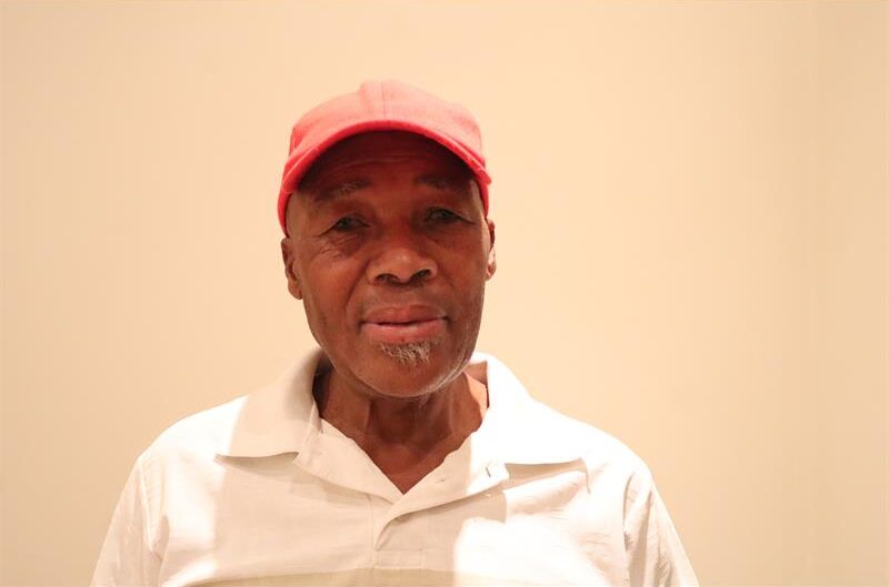 A man wearing a white golf tshirt and a red cap