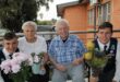 Twee jong seuns hou blomme aan bejaarde man en vrou