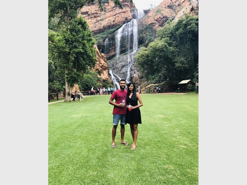 A black man and black woman standing in front of waterfall at the botanical gardens. 