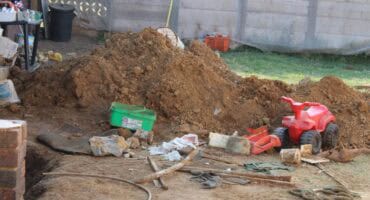 A picture showing a mound of sand with a red toy motorcycle standing among the sand