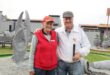 A old lady in a red jacket standing next to a man wearing a white jacket