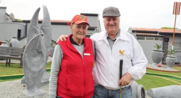 A old lady in a red jacket standing next to a man wearing a white jacket