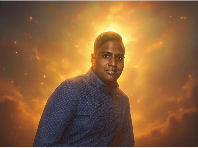 An indian boy smiling wearing a jean shirt.