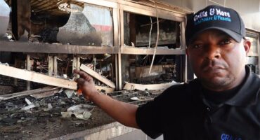 a man standing next to a fire damaged property