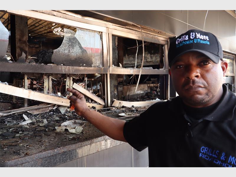 a man standing next to a fire damaged property