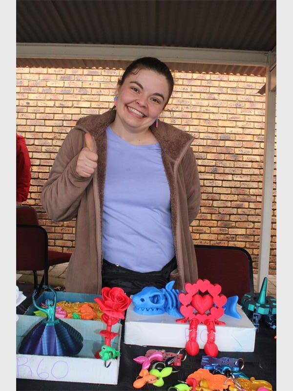 A white woman giving a thumbs up behind a table decorated with crafts.