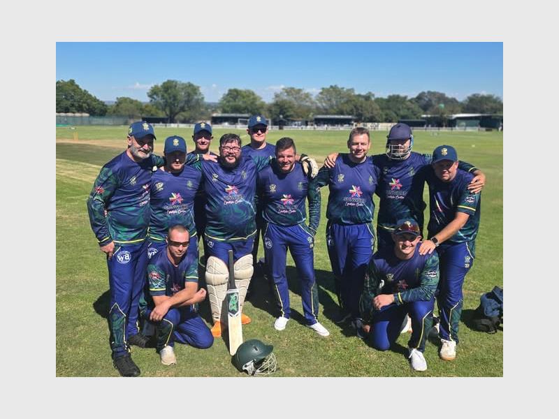 A team of cricket players dressed in blue kit huddled together for a photo.