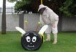 Man wearing a bee suit standing next to a bee made out of tyres