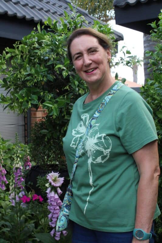 Woman wearing green shirt standing next to flowers