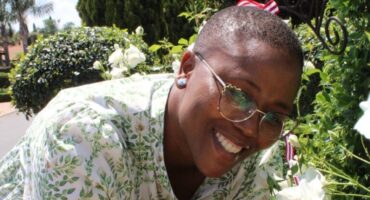 Black woman with glasses holding a white rose between her hands