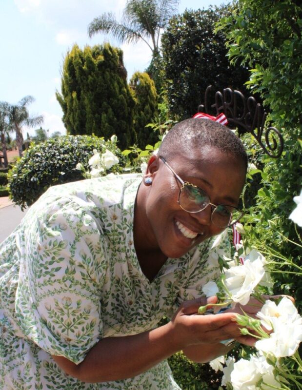 Black woman with glasses holding a white rose between her hands