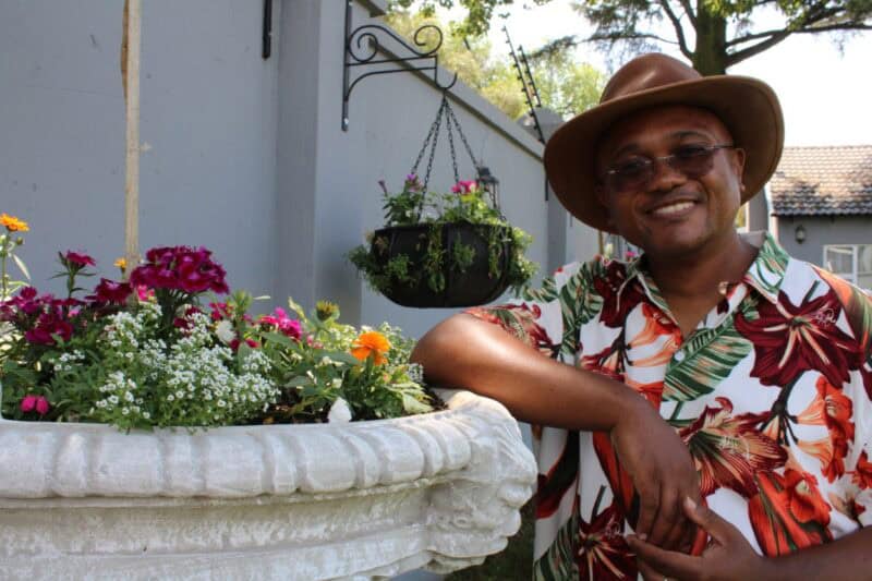 Man wearing a floral shirt standing next to seedlings