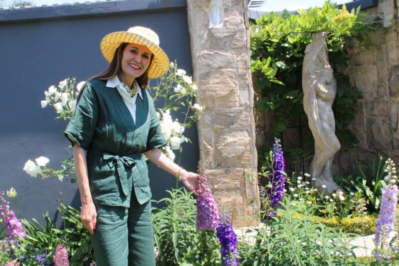 Woman wearing a hat standing next to blooming flowers