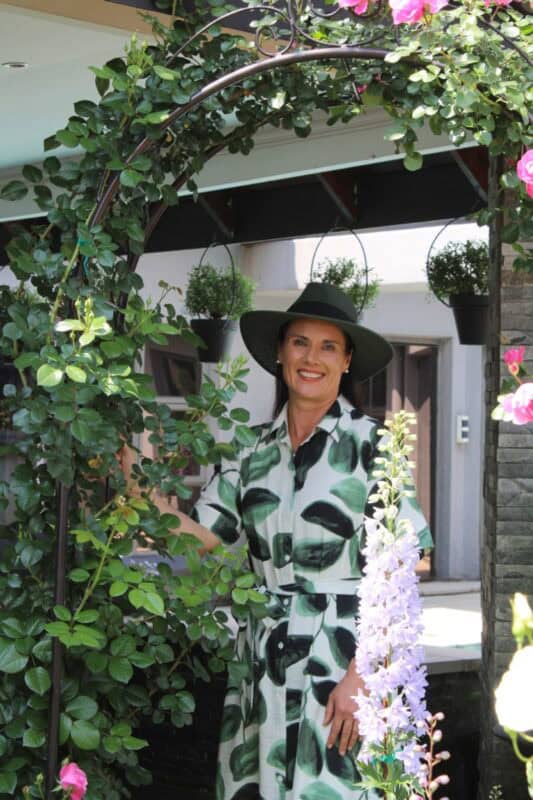 Woman wearing a dress and sun hat standing in a garden