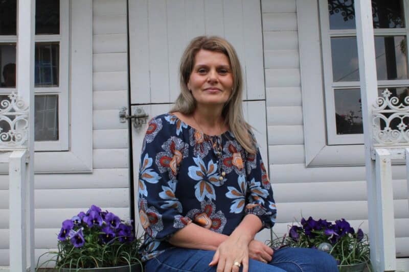Woman sitting a white playhouse next to pansies