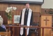 White reverend standing in front of a church congregation