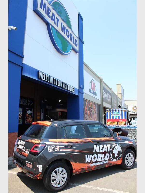 A Suzuki Swift branded Meat World parked outside a Meat World store.