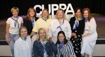 Group of women sitting in front of letters that spell CUPPA