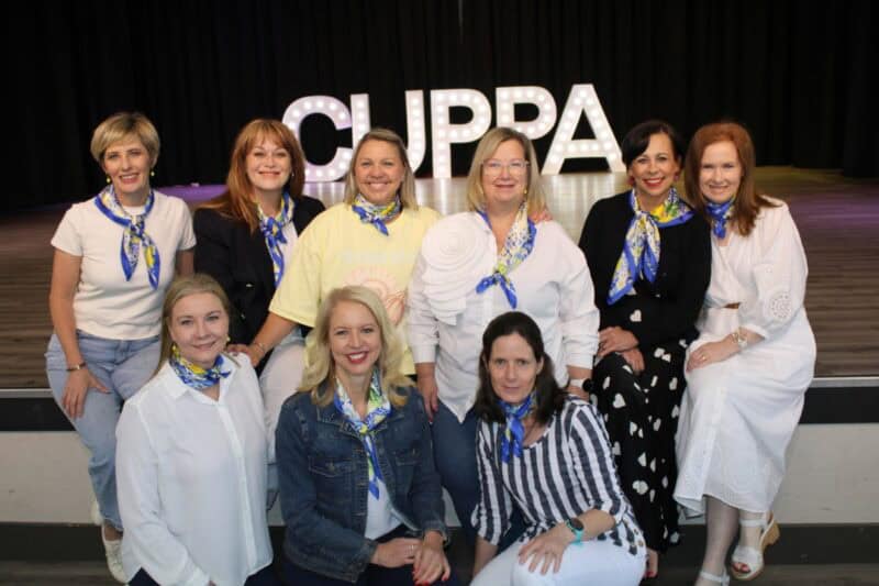 Group of women sitting in front of letters that spell CUPPA