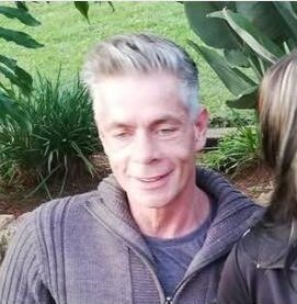A man with gray hair and a gray jersey