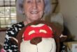 Elderly woman holding a soft toy dressed as a superhero