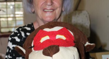 Elderly woman holding a soft toy dressed as a superhero