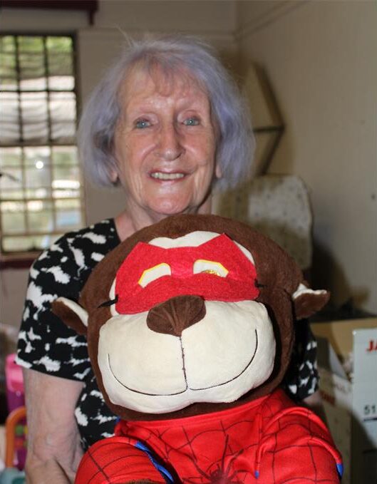 Elderly woman holding a soft toy dressed as a superhero