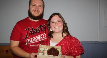 Man and woman dressed in red holding a box