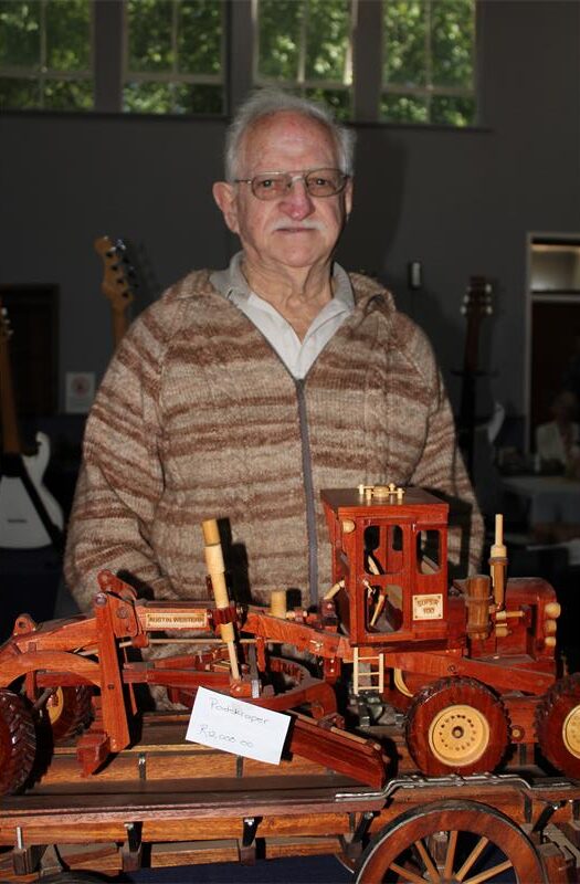 Elderly man standing with a wooden road scraper
