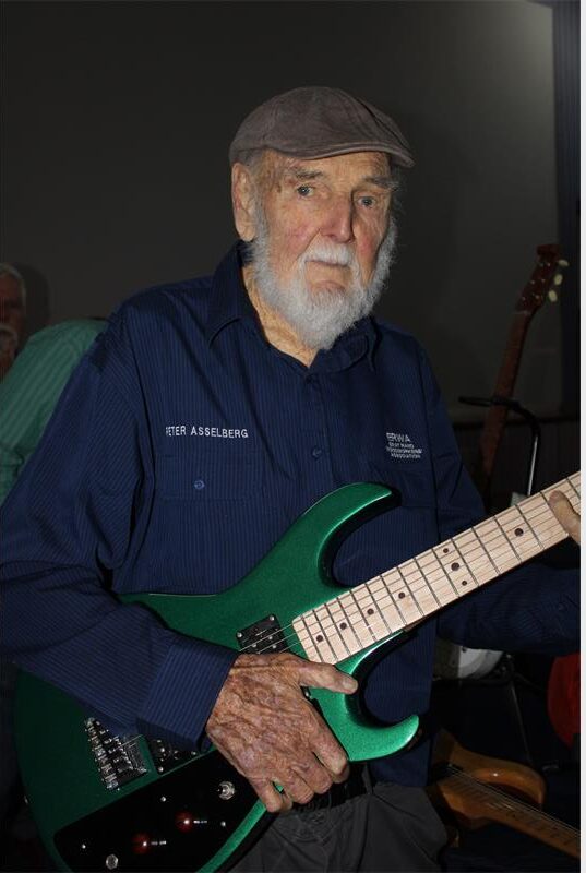Elderly man holding a green guitar