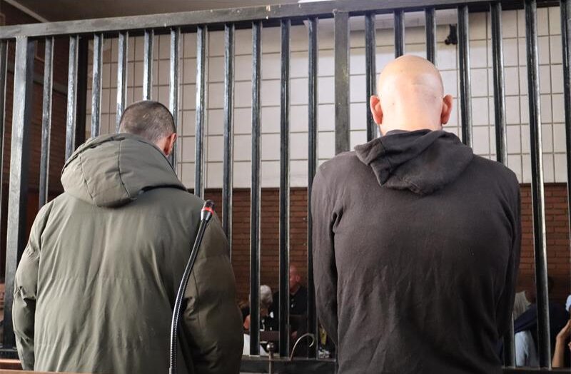 Two man standing next to each other one in a green jacket and one in black hoodie.