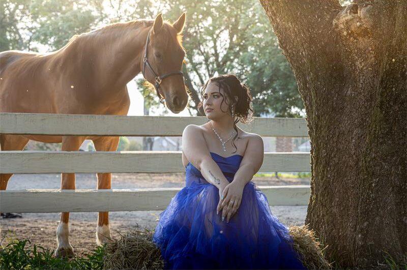 Girl in evening wear sitting with a horse